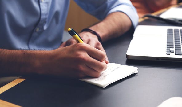 man taking notes and laptop 